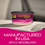 Single California Scents Coronado Cherry air freshener can sitting on a car seat with large pink banner reading manufactured in USA