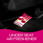 California Scents Coronado Cherry Scent Bloc placed under a car seat on a black floor mat labeled as under-seat freshener