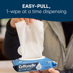 Person pulling a single Cottonelle wipe from a blue flip-top pack demonstrating easy-pull, one-wipe dispensing.