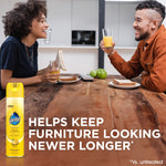Two people sitting at a wood table with a Pledge lemon polish can pictured on the table and text 'Helps keep furniture looking newer longer'