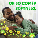 Couple cuddling on couch with green floral accents and large text promoting comfy softness for Gain fabric softener