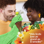 Man smelling a green towel held by a smiling woman with colorful floral graphics and a testimonial quote