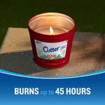 Cutter red outdoor candle burning on a stone surface showing label and warm glow