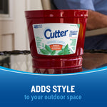 Close-up of a red Cutter outdoor candle on a glass table with label visible and 'adds style' text