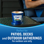 Burning Cutter outdoor candle in blue tub on a patio table with blurred person in background and patio text.