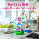 Dapple Baby bottle and dish soap refill pouch staged on a kitchen sink drying rack with faucet running