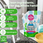 Dapple Baby bottle and dish soap refill pouch on a countertop next to a bottle brush and baby feeding items