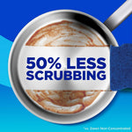 Top-down frying pan being partly cleaned with a blue sponge and bold text reading “50% LESS SCRUBBING”