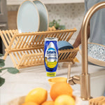 Lifestyle kitchen scene with a Dawn Platinum Clean Lemon bottle on counter near a dish rack and sink
