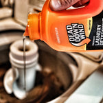 Close-up action shot of orange Dead Down Wind detergent being poured into a washer dispenser from a tilted bottle