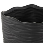 Close-up view of the irregular wavy rim and textured ribbed surface of a black ceramic planter