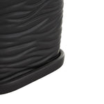 Detail close-up of the textured wavy ribs and attached saucer edge on a black ceramic planter