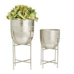 Two brushed silver dome metal planters on removable matching metal stands, one filled with green hydrangea