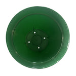 Top-down view into a green plastic planter showing interior base and four circular drainage hole impressions