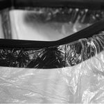 Detail close-up of a trash bag secured under the black plastic rim of a collapsible bag holder