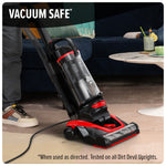 Upright Dirt Devil vacuum on a carpeted floor with text overlay "VACUUM SAFE" and small usage disclaimer at bottom.