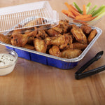 Aluminum disposable pan filled with chicken wings, clear plastic lid propped open and dipping sauce nearby