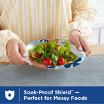 Person holding a Dixie patterned paper plate filled with a fresh green salad, shown on a tabletop.