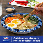 Dixie Ultra patterned paper bowl filled with ramen, soft-boiled eggs and vegetables, chopsticks lifting noodles
