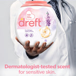 Hand of a person in a white coat holding a Dreft pacs container with text about dermatologist-tested scent