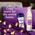 Downy Cuddle Weather bottle and Febreze Luxe air spray shown on a purple pillow with text 'Cozy scent for the entire home'.