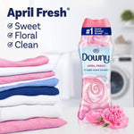 Downy April Fresh bottle next to folded laundry and pink flowers with copy listing 'April Fresh' and descriptors sweet, floral, clean