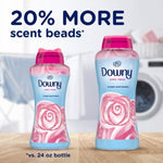 Two Downy April Fresh in-wash scent booster bottles on a wooden surface with text advertising 20% more scent beads