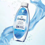 Downy Rinse & Refresh Ocean Mist bottle with blue fabric-like ribbon and water droplets in background