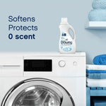 Downy Ultra Free & Gentle bottle on top of a washing machine with text 'Softens Protects 0 scent' and folded towels nearby.