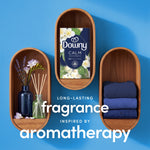 Downy CALM box displayed inside wooden oval niches with folded linens and reed diffuser, promoting aromatherapy fragrance