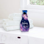 Downy Infusions Calm bottle staged next to folded white towels on a laundry surface by a window