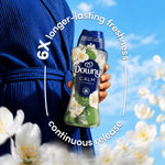 Hand holding a Downy Calm bottle against a blue sky with circular text highlighting longer-lasting freshness