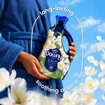 Hands holding a Downy Fresh Calm bottle wearing a blue robe, surrounded by white flowers and text 'long-lasting soothing aroma'.