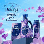 Downy brand display showing a Downy CALM box, liquid bottle, and scent booster with petals and 'amplify your freshness'.