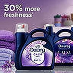Promotional image showing multiple Downy Calm lavender bottles with text proclaiming enhanced freshness on a purple background.