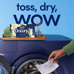 downy calm white tea & bergamot dryer sheets box on laundry machine with hand placing a sheet; towel and reed diffuser on a tray; background text reads toss, dry, wow