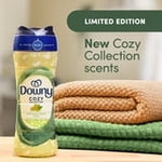 Downy Cozy scent booster bottle beside folded towels with a banner reading New Cozy Collection scents