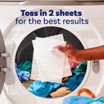 Hand placing two dryer sheets into a front-loading dryer with clothes and headline 'Toss in 2 sheets'