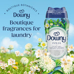 Downy Folia scent booster bottle set against a sky background with floral foreground and 'Boutique fragrances for laundry' headline