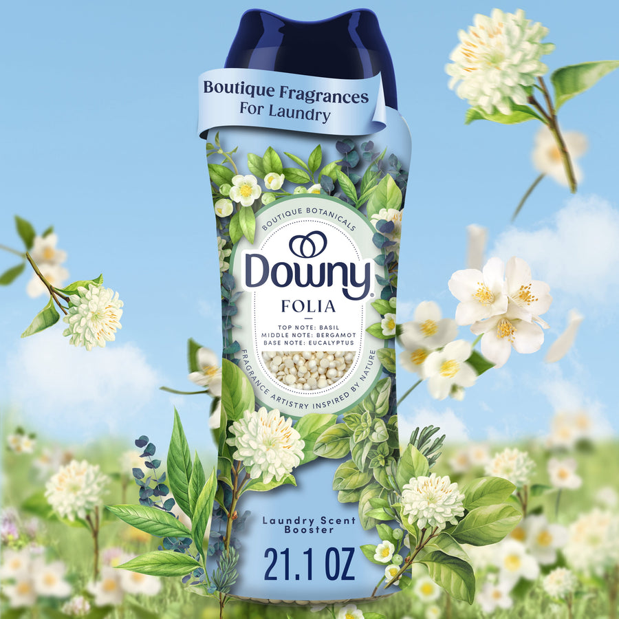 Close-up of a Downy Folia in-wash scent booster bottle with botanical floral artwork on a blue sky background