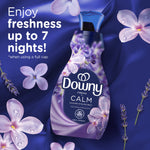 Downy Fresh Calm bottle on a purple fabric backdrop with floral accents and text about freshness lasting up to seven nights