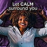 Person smiling with arms raised over a purple pillow with headline 'Let CALM surround you' promoting Downy Calm.
