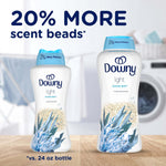 Two Downy Light Ocean Mist bottles on a table with text "20% MORE scent beads*" and a blurred laundry room background