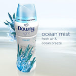 Styled product image of Downy Light Ocean Mist bottle against a soft ocean background with 'ocean mist' text