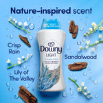 Downy Light Ocean Mist bottle surrounded by imagery of lily-of-the-valley, sandalwood and water droplets explaining nature-inspired scent notes