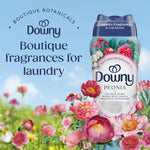 Downy Peonia scent booster bottle displayed in a floral field with large peony illustrations and promotional text about boutique fragrances
