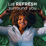 Overhead lifestyle image of a smiling person on green sheets with text ‘Let REFRESH surround you’
