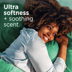Smiling person resting on green bedding with text promoting ultra softness and soothing scent