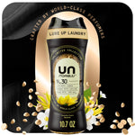 Black bottle of Downy Unstopables N.30 scent booster with floral accents and floating scent beads on a dark background