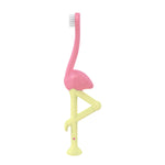Front-facing view of Dr. Brown’s pink flamingo toddler toothbrush with soft white bristles and yellow leg-shaped handle